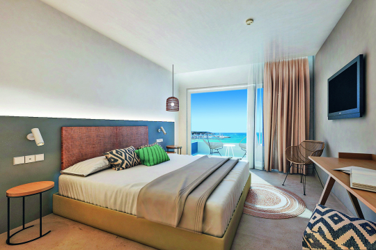 Hotelzimmer im Boho Stil mit Blick über das Bett hin zum Balkon mit Meerblick